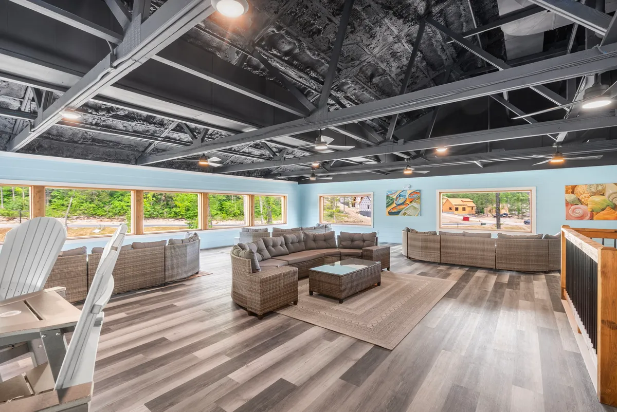 A large sectional sofa is arranged to create an inviting area for social gatherings or movie nights. The room is filled with natural light from big windows, and a coffee table and art on the walls add to the cozy yet vibrant atmosphere.